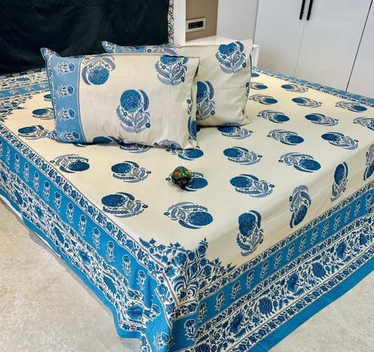 Blue and white patterned bedspread with matching pillows on a bed.