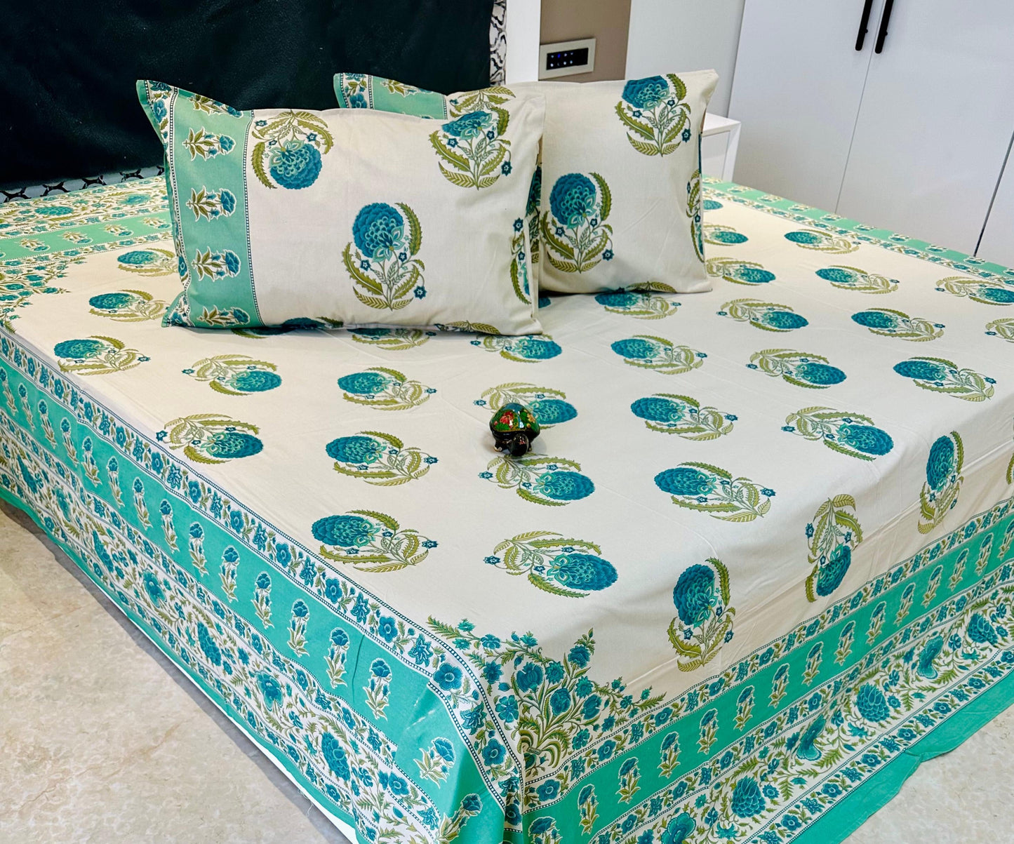 Cotton Bedspread with green and blue patterns on a bed in a room.