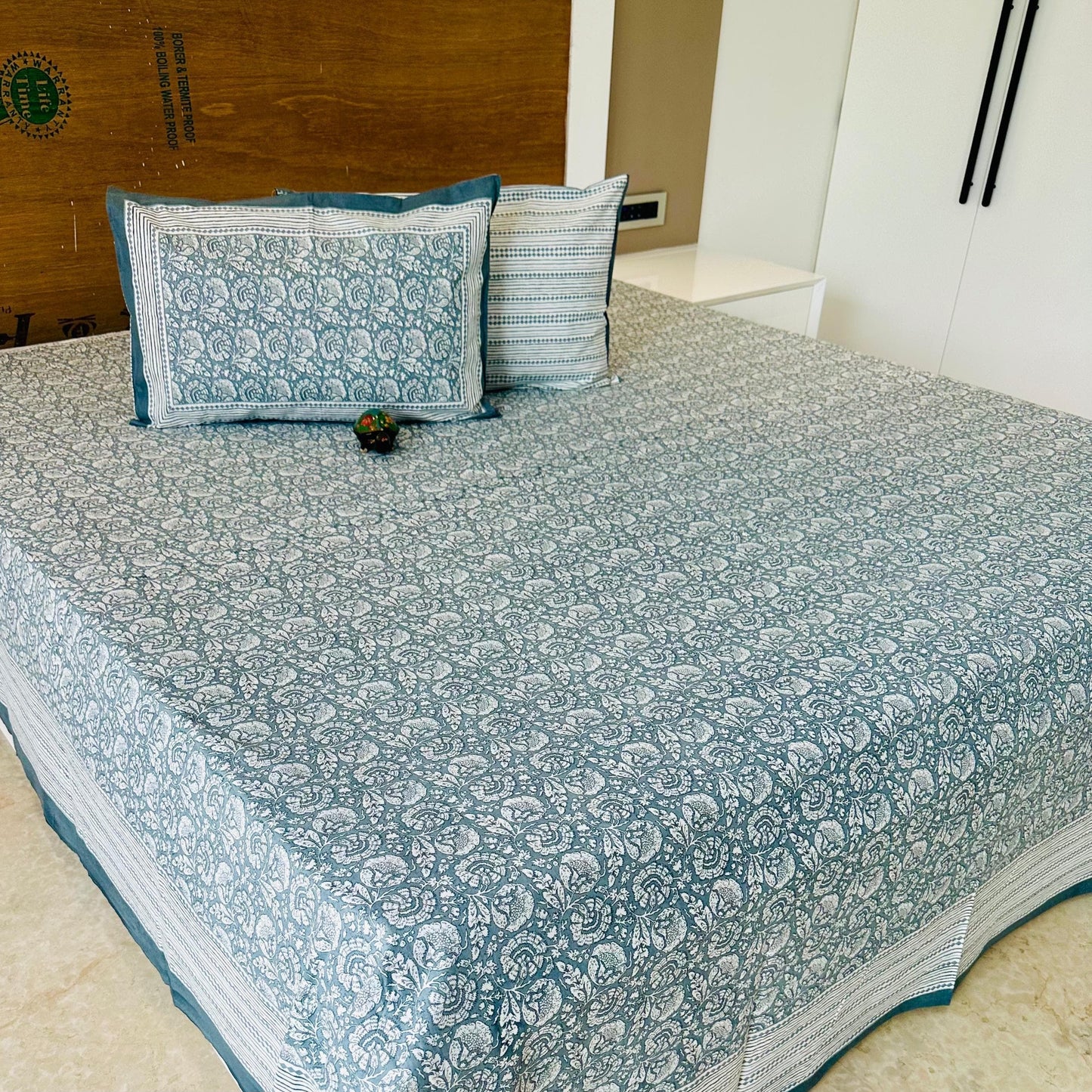Blue cotton Bedspread with floral pattern on a bed, featuring 'Shahi Collection' branding.