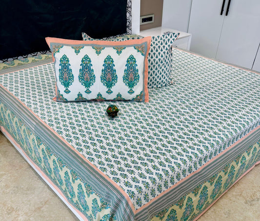 Decorative bedspread with green and pink patterns on a bed.